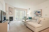 This single-story, 2-bedroom, 2-bathroom residence offers a comfortable and cohesive layout across a well-utilized footprint. The living room serves as a central gathering space, featuring a tiled fireplace, plush carpeting, and sliding glass doors that open to a private patio with outdoor views — allowing natural light to fill the room. The adjacent kitchen is equipped with white cabinetry, granite countertops, stainless steel appliances including a refrigerator, dishwasher, and range, and tile flooring. A dedicated dining area nearby features a round marble-top table beneath an elegant chandelier, complemented by tasteful artwork. The spacious primary bedroom includes direct access to a walk-in closet and an en-suite bathroom outfitted with a dual-sink vanity, soaking tub, and multiple windows that bring in natural light. The second bedroom offers ample space, a large window with garden views, and built-in shelving. The second bathroom features tile flooring, a single-sink vanity with white cabinetry, and a shower-tub combination. Two hallways and additional closets provide practical storage throughout. The overall ambiance is bright, neutral, and move-in ready.