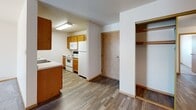This single-floor residential unit offers a practical and well-organized layout designed for comfortable everyday living. The kitchen is equipped with oak-toned cabinetry, a double sink, white appliances including a refrigerator, electric range, and microwave, and durable wood-look flooring that extends through the entryway and main living areas. A coat closet with built-in shelving is conveniently located near the front entrance.

The living areas feature neutral-toned carpet, textured ceilings, and baseboard heating, creating a warm and functional environment. Bedrooms are carpeted and include ample closet space—one room features a walk-in closet with multiple shelving tiers and hanging rods for organized storage, while additional bedrooms offer standard closets with built-in rods and shelves.

The bathroom is well-appointed with a warm wood vanity, white countertop, a full tub and shower combination, and wood-look tile flooring that adds a clean, modern touch. A dedicated in-unit laundry area houses a full-size washer and dryer side by side beneath an overhead storage shelf, adding significant convenience. Natural light filters into the bedrooms through sliding windows, with exterior views of the surrounding neighborhood. The overall aesthetic is clean, neutral, and move-in ready.