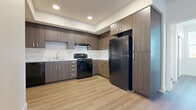 This well-designed 2-bedroom, 2-bathroom unit offers a thoughtfully organized single-floor layout that maximizes functionality. Light-toned luxury vinyl plank flooring flows consistently throughout, creating a cohesive and easy-to-maintain living environment.

The kitchen is a standout feature, equipped with medium-toned wood-grain cabinetry extending from base to ceiling, a marble-style tile backsplash, light stone countertops, and a full suite of black appliances including a refrigerator, electric range, dishwasher, and built-in range hood. Recessed lighting illuminates the space effectively.

Both bedrooms are bright and airy, benefiting from large windows with horizontal blinds that allow ample natural light. The primary bedroom includes a sliding-door closet with wire shelving, offering practical storage. The second bedroom features a corner window configuration, enhancing its open feel.

The two bathrooms maintain a consistent modern aesthetic, each featuring wood-grain vanities with stone-topped counters, large mirrors, brushed nickel fixtures, and full tub-shower combinations. The clean white walls and vinyl plank flooring keep both bathrooms feeling fresh and contemporary.

A hallway connects the living areas seamlessly, with a louvered utility closet providing additional storage. Overall, the unit presents a clean, modern design with consistent finishes throughout.