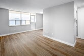 Located at 70 Park St E, Unit 1406 in Mississauga's Port Credit area, this single-floor unit has been thoughtfully updated with contemporary finishes throughout. The interior features light-toned laminate flooring that runs consistently across the living spaces, complemented by soft grey walls and clean white trim, creating a cohesive and modern aesthetic.

The open living area is generously proportioned, benefiting from natural light through large windows that illuminate the space. The layout connects living and sleeping areas in a functional arrangement, as visible in the 3D floor plan overview.

The kitchen has been renovated to a modern standard, showcasing flat-panel white cabinetry both above and below the counter, a sleek white quartz countertop, a white subway tile backsplash, a stainless steel undermount sink with a pull-down faucet, and a black glass electric cooktop with built-in appliances.

The bedrooms are well-sized, each featuring light hardwood-style flooring, windows for natural light, and ample closet space. One bedroom includes a full-width sliding door closet with built-in shelving. The bathroom is clean and bright, finished with white tile, a soaker tub with shower, a vanity with quartz countertop, and a small window for ventilation.