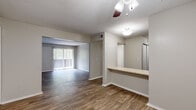 This single-floor residence offers a practical and well-organized layout designed for comfortable everyday living. The main living and dining areas are connected by an open passageway, creating a seamless flow throughout the space. Rich wood-style flooring runs through the living areas, complemented by neutral gray walls and ceiling fans that add both function and a casual aesthetic. A pass-through counter connects the living area to the kitchen, which is equipped with warm brown cabinetry, light countertops, a double-basin sink, a dishwasher, and a full-size refrigerator — all finished with matching wood-style flooring. Sliding glass doors in the living room open with vertical blinds, inviting natural light and providing views of surrounding greenery. The bedrooms offer a quieter retreat, with plush carpeting underfoot, generous wall space, and windows fitted with blinds that allow for adjustable natural light. One bedroom features its own ceiling fan. The bathroom includes a full tub and shower combination with clean white tile surround, complemented by wood-style flooring. Throughout the unit, consistent neutral tones and practical finishes create a cohesive, move-in-ready environment.