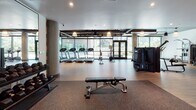 Located in the heart of Hollywood at 1331 N Cahuenga Blvd, this well-appointed fitness center offers a comprehensive workout environment across a single thoughtfully designed floor. The space is divided into distinct training zones, each catering to different aspects of physical fitness.

The main cardio area features a row of treadmills and Concept2 RowERG rowing machines positioned along a floor-to-ceiling glass wall, flooding the space with natural light and offering views of the surrounding neighborhood. Exposed ductwork along the dark ceiling lends an industrial-modern aesthetic, complemented by warm pendant lighting and durable wood-finish flooring throughout.

Adjacent to the cardio zone, a spacious strength training area houses a variety of cable machines and multi-function equipment, supported by round concrete columns that add to the industrial character of the space.

A dedicated free weights room is enclosed by sleek glass barn-style sliding doors, providing a semi-private environment for focused strength training. Inside, floor-to-ceiling mirrors line one wall alongside a full dumbbell rack and a power rack with an adjustable bench, all set on rubber flooring for safety and performance.

Together, these zones create a fully equipped, modern fitness facility designed to support a wide range of training needs in a clean, well-lit, and professionally appointed setting.