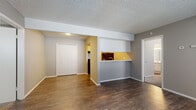 This 2-bedroom, 2-bathroom single-floor unit offers a practical and functional layout across a compact yet efficient footprint. The living room serves as the central gathering space, featuring durable dark wood-look vinyl flooring, neutral gray walls, and a textured ceiling. A distinctive pass-through window with a marble-patterned countertop connects the kitchen to the living area, creating an open and communicative feel between the two spaces. The kitchen is equipped with white cabinetry, a stainless steel sink, and a mirrored backsplash that adds depth and reflects natural light from a nearby window. A second kitchen area provides additional utility and storage. Both bedrooms are carpeted for comfort, each featuring neutral gray walls, textured ceilings, and windows that allow natural light to filter in. The primary bedroom includes access to its own bathroom, which features a marble-patterned vanity countertop, white cabinetry, and wood-look flooring. Each bedroom benefits from its own dedicated closet with built-in shelving and hanging rods. A hallway connects the main living areas to the bedrooms and bathrooms, ensuring a logical and private flow throughout the unit. Overall, the space presents a clean, move-in-ready interior with consistent finishes throughout.