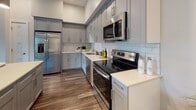 Located at 1 Marys Way in Lincoln, Massachusetts, this single-floor residence offers a refined living experience marked by modern design and quality finishes throughout. The open-concept layout flows seamlessly from room to room, anchored by rich hardwood flooring and a neutral color palette that creates a warm, cohesive atmosphere.

The kitchen is a standout feature, equipped with sleek gray shaker cabinetry, white quartz countertops, a classic subway tile backsplash, and a full suite of stainless steel appliances. A spacious center island with bar seating serves as both a functional workspace and a casual dining hub, complemented by stylish pendant lighting overhead.

The living area impresses with soaring vaulted ceilings and large windows that frame lush outdoor views, filling the space with natural light. A conveniently integrated laundry closet with a stacked washer and dryer adds practicality to this inviting room.

The bedrooms are comfortably carpeted and feature vaulted or tray ceiling details, generous closet space, and windows with outdoor views. A dedicated home office with hardwood flooring offers a bright, versatile space.

Two well-finished bathrooms serve the residence — one with a walk-in shower featuring white subway tile, and another with a full soaking tub. Both are appointed with dark wood vanities and light tile flooring, lending a clean, polished feel throughout.