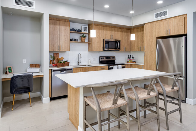 Cocina de concepto abierto con encimeras de cuarzo, isla, electrodomésticos de acero inoxidable, placa para salpicaduras de azulejo y trabajar desde el hogar de un rincón - Avalon Doral