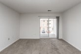This single-floor unit offers a well-organized, functional layout with a clean, neutral palette throughout. The living area is generously sized, featuring soft wall-to-wall carpeting, a textured ceiling, and a sliding glass door that opens to a private balcony — allowing natural light to fill the space while providing a view of the surrounding community. The open-concept design connects the living area seamlessly to the kitchen, which is defined by a breakfast bar peninsula, white cabinetry, laminate countertops, and hardwood-style flooring. Appliances include an electric range, built-in microwave, and refrigerator, making the kitchen both practical and efficient. The bedroom is a comfortable retreat, offering plush carpeting, a ceiling fan with light fixture, and a large window that brings in additional natural light. A walk-in closet provides ample storage, complementing the overall functionality of the room. The bathroom is well-appointed with a full soaking tub and shower combination, a wide vanity with under-sink storage, a large mirror, and tile flooring. Throughout the unit, the consistent use of neutral tones and clean finishes creates a bright, move-in-ready atmosphere well-suited for everyday living.