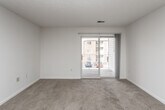 This single-floor unit offers a well-organized, functional layout with a clean, neutral palette throughout. The living area is generously sized, featuring soft wall-to-wall carpeting, a textured ceiling, and a sliding glass door that opens to a private balcony — allowing natural light to fill the space while providing a view of the surrounding community. The open-concept design connects the living area seamlessly to the kitchen, which is defined by a breakfast bar peninsula, white cabinetry, laminate countertops, and hardwood-style flooring. Appliances include an electric range, built-in microwave, and refrigerator, making the kitchen both practical and efficient. The bedroom is a comfortable retreat, offering plush carpeting, a ceiling fan with light fixture, and a large window that brings in additional natural light. A walk-in closet provides ample storage, complementing the overall functionality of the room. The bathroom is well-appointed with a full soaking tub and shower combination, a wide vanity with under-sink storage, a large mirror, and tile flooring. Throughout the unit, the consistent use of neutral tones and clean finishes creates a bright, move-in-ready atmosphere well-suited for everyday living.