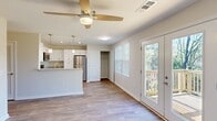 This efficiently designed 3-bedroom, 2-bathroom single-story home makes excellent use of its footprint with a thoughtful, functional layout. The open-concept living and kitchen area serves as the heart of the home, featuring durable hardwood-style flooring, neutral wall tones, and a ceiling fan that enhances airflow throughout. French doors in the living area open directly onto a private outdoor deck, offering natural light and wooded views that bring a sense of openness to the space.

The kitchen is well-appointed with white shaker-style cabinetry, granite-look countertops, stainless steel appliances including a refrigerator, microwave, and range, and a peninsula with a sink — ideal for both cooking and casual dining.

The three bedrooms are carpeted for comfort and each includes a ceiling fan and window with blinds, allowing for natural light and ventilation. The primary bedroom offers a generous footprint relative to the overall home. Both bathrooms are finished in a clean, white palette with hardwood-style tile flooring, a tub-shower combination featuring white subway tile surround, and brushed nickel fixtures.

A dedicated laundry area with washer and dryer hookups and built-in wire shelving adds everyday convenience, rounding out this well-organized, move-in ready home.