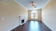 This single-story unit in Germantown, Tennessee, offers a well-designed layout that balances comfort and functionality. The living room serves as the centerpiece of the space, featuring rich, dark hardwood-style flooring, a classic tile-surround fireplace with a white decorative mantel, and a striking arched window that frames outdoor greenery and fills the room with natural light. Crown molding and a ceiling fan add refined finishing touches, while the textured ceiling completes the traditional aesthetic.

The open layout connects the living area to a dining space and kitchen, which is outfitted with white cabinetry, granite-style countertops, a double stainless steel sink, and stainless steel appliances including a refrigerator, range, and dishwasher. Dark hardwood-style flooring carries throughout these areas, creating visual continuity.

The bedroom features vaulted ceilings, neutral carpet, a ceiling fan, and a window providing natural light. A closet provides convenient storage. The bathroom includes a full tub and shower combination with a clean, simple surround. Throughout the unit, warm neutral tones and consistent finishes create a cohesive and comfortable living environment.