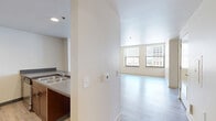 Located in the heart of Kansas City, MO, this two-bedroom, one-bathroom unit offers a well-organized single-floor layout designed for comfortable urban living. The open-concept kitchen and living area serve as the central hub of the space, where rich dark wood cabinetry, a peninsula with bar-height countertops, stainless steel appliances, and recessed lighting combine to create a functional yet stylish environment. Light wood-style hard flooring runs throughout the main living areas, lending a clean and modern aesthetic.

The living area is generously proportioned, with large windows that invite abundant natural light and frame views of the surrounding downtown Kansas City skyline. Both bedrooms are carpeted for comfort, each featuring multiple windows with views of the city's historic architecture. The primary bedroom offers a spacious footprint with dual windows, while the second bedroom is equally well-lit and versatile.

The full bathroom is thoughtfully appointed with a rich wood vanity, a large mirror, and accessibility features including grab bars, reflecting both practicality and inclusive design. A dedicated closet provides additional storage. The unit's neutral color palette, modern finishes, and downtown location make it a compelling urban residence.
