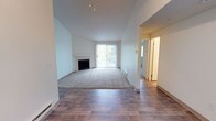 Located at 510 Stevens Ave SW, Unit E304 in Renton, Washington, this single-floor residence offers a well-organized and comfortable layout with a variety of thoughtful design details throughout.

The living area serves as the heart of the space, featuring soaring vaulted ceilings that enhance the sense of openness and volume. A tiled fireplace anchors one wall, providing a classic focal point and cozy atmosphere. Natural light pours in through a large sliding glass door that opens onto a private balcony, offering a pleasant outdoor connection and views of the surrounding greenery. The living area transitions seamlessly between hardwood-style flooring near the entry and soft carpeting in the main lounge area, creating distinct zones within the open floor plan.

Baseboard heating units are present along the walls, ensuring consistent warmth throughout the cooler months. The textured ceiling adds a traditional touch to the interior. A hallway visible from the main living area leads to additional rooms, suggesting a practical and functional layout that accommodates everyday living with ease.

Overall, the space strikes a balance between comfort and functionality, with architectural features like vaulted ceilings and a fireplace elevating the character of the interior beyond the standard.