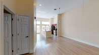This single-story unit presents a well-designed, open-concept layout with light hardwood flooring throughout, creating a cohesive and airy feel across all rooms. The living area is generously proportioned, featuring elevated ceilings, recessed lighting, a ceiling fan, and a louvered closet — offering both comfort and storage convenience.

The kitchen serves as a central hub of the space, distinguished by its rich dark wood cabinetry, granite countertops, and a large island with a built-in sink. Stainless steel appliances — including a refrigerator, range, and microwave — complete the well-equipped culinary space. Tall clerestory windows above the French doors flood the kitchen with abundant natural light while framing outdoor views, contributing to a bright and open atmosphere.

Two full bathrooms are finished with tile-surround tub-shower combinations and wood-toned cabinetry. One bathroom features a pedestal sink and wall-mounted storage cabinet, while the other offers a more compact, functional layout. Additional bedrooms provide neutral, versatile spaces with hardwood-style flooring and warm beige walls, adaptable for various uses. Throughout, the design balances practical functionality with clean, contemporary finishes.