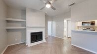 This single-story, one-bedroom, two-bathroom residence in Austin, TX offers a thoughtfully designed layout across a compact yet functional floor plan. The combined kitchen and living area serves as the heart of the home, highlighted by eye-catching herringbone-patterned hardwood-style flooring that extends throughout. The living room features a classic wood-burning fireplace with a white tile surround and mantel, flanked by built-in open shelving—ideal for display or storage. A ceiling fan overhead adds comfort and airflow to the space, which also benefits from natural light streaming through a large window near the entryway.

The galley-style kitchen is efficiently arranged with white cabinetry, quartz-style countertops, a stainless steel sink, and a full suite of stainless steel appliances including a refrigerator, range, and over-the-range microwave.

The bedroom is a calm, carpeted retreat with a ceiling fan, a window offering outdoor views of mature trees, and access to a spacious walk-in closet outfitted with wire shelving on both sides. Two bathrooms serve the unit, each featuring a tub/shower combination with white tile surrounds and light, neutral finishes throughout. The overall aesthetic is clean, neutral, and move-in ready.