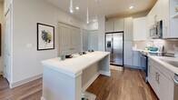 Located at 400 Buford Hwy in Suwanee, GA, this well-appointed 2-bedroom, 2-bathroom residence offers a cohesive modern design with warm, neutral tones and hardwood-style flooring throughout. The open-concept kitchen is a standout feature, showcasing stainless steel appliances including a French door refrigerator and gas range, a tile backsplash, light wood cabinetry, and a spacious quartz-topped island with seating — ideal for both cooking and casual dining. Pendant lighting above the island adds a contemporary touch. The primary bedroom is a comfortable retreat, featuring a decorative wall panel accent, large windows, and direct access to a well-sized en-suite bathroom. The primary bath is finished with a quartz double vanity, light wood cabinetry with brushed nickel hardware, and a walk-in closet with built-in shelving. The second bedroom offers natural light through large windows, a ceiling fan, and its own dedicated closet. The second bathroom mirrors the refined aesthetic with a quartz vanity and a tub-shower combination accented by stylish tile surround. Dedicated closets in each bedroom and a hallway connecting all rooms complete this functional, modern layout in the heart of Suwanee.