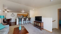 Located on Heritage Drive in Marshfield, Wisconsin, this single-floor unit offers a practical and comfortable layout designed for everyday living. The open-concept living area features plush carpeting, a ceiling-height partition wall that separates it from the kitchen, and flows seamlessly into the dining space, which is finished with hardwood-style flooring and accented by a ceiling fan overhead.

The kitchen is well-appointed with warm wood cabinetry, granite-style countertops, stainless steel appliances including a refrigerator, microwave, and range, as well as a double-basin sink and dishwasher. A breakfast bar with seating connects the kitchen to the living area, making it ideal for casual dining or entertaining.

The bedrooms are carpeted and filled with natural light from large windows with blinds and curtain panels. Each room provides a quiet, comfortable retreat with baseboard heating for year-round comfort.

The bathroom features matching wood cabinetry, granite-style counters, a walk-in shower, and hardwood-style flooring that ties the space together cohesively. A dedicated laundry room houses a full-size washer and dryer along with wire shelving, adding everyday convenience directly within the unit.