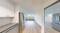 Located on the 6th floor at 155 Wellesley Street East in Toronto's vibrant Church-Wellesley neighbourhood, this one-bedroom, one-bathroom unit offers a well-planned layout with clean, modern finishes throughout. The living area is bright and open, featuring light-toned hardwood flooring, crisp white walls, and large floor-to-ceiling windows that flood the space with natural light and frame sweeping views of the Toronto skyline. A baseboard heating system runs along the perimeter, ensuring year-round comfort. The living space flows directly toward the kitchen area, which is visible in the background with white cabinetry offering functional storage. The generously sized bedroom continues the same hardwood flooring and neutral palette, and is fitted with a full-width mirrored sliding closet that enhances the sense of space while providing ample storage. The four-piece bathroom is tastefully renovated, featuring classic white subway tile surround on the tub and shower combination, stone-look floor tiles, a white vanity, and a window that brings in natural light while offering a glimpse of the city. The overall ambiance is clean, bright, and move-in ready, ideal for those seeking urban convenience in the heart of Toronto.