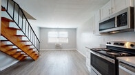 This two-floor residence in Bridgeport, CT offers a thoughtfully updated interior with a clean, contemporary aesthetic throughout. The main level features an open-concept living and dining area with light gray walls, smooth white ceilings, and light-toned wood-style flooring that extends across the space. A staircase with a sleek black metal railing connects the two floors, adding a modern architectural detail to the layout. Natural light enters through a window fitted with white blinds, complementing the bright, airy feel of the living area.

The kitchen is well-appointed with white shaker-style cabinetry, gray quartz-style countertops, a stainless steel single-basin sink with a flexible faucet, and a full suite of stainless steel appliances including a range, microwave, and dishwasher. Ample upper and lower cabinet storage makes the kitchen both functional and visually cohesive.

Upstairs, the bedroom offers generous closet space via full-width bi-fold white closet doors and continues the same light wood-style flooring found throughout the home. The bathroom is finished in white tile, featuring a tub-shower combination, a white vanity with cabinet storage, a wall mirror, and wood-style flooring. The overall design is consistent, fresh, and move-in ready.