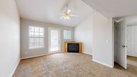 Located at 2001 W 6th St in Lawrence, Kansas, this one-bedroom, one-bathroom residence offers a thoughtfully arranged single-floor layout with a warm and functional design throughout. The combined kitchen and living area serves as the heart of the home, featuring soaring vaulted ceilings that lend a sense of openness well beyond the unit's compact footprint. A ceiling fan provides comfort overhead, while a corner fireplace with a wood-toned surround adds a welcoming focal point to the living space. A glass-paneled door opens to an outdoor balcony, allowing natural light to fill the room alongside dual windows fitted with blinds. The galley-style kitchen is efficiently designed with warm oak cabinetry, dark countertops, tile flooring, and a full suite of white appliances including a refrigerator, range, built-in microwave, and dishwasher. The bedroom offers a comfortable, carpeted retreat with a standard closet and a window that frames views of the surrounding neighborhood. The bathroom is finished with tile flooring and a tub-shower combination enclosed by sliding glass doors. Soft carpet flows through the main living areas, contributing to the unit's cozy, residential ambiance.
