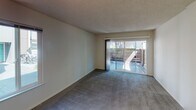 Located at 2949 Portage Bay W in Davis, CA, this ground-floor unit offers a practical and comfortable single-level layout. The living area is generously sized, featuring plush wall-to-wall carpeting, neutral-toned walls, and a textured ceiling. A large sliding glass door floods the space with natural light and opens directly onto a private patio enclosed by a slatted wood fence, providing a pleasant outdoor retreat. The kitchen is efficiently designed with a galley-style layout, offering white cabinetry, granite-look countertops, a stainless sink, and white appliances including a range and dishwasher. A window above the counter brings in additional natural light. Adjacent to the kitchen is a dining area with carpeted flooring, a overhead light fixture, and a window with views of the surrounding neighborhood. The bedroom is well-proportioned with soft carpeting and a sliding window that frames greenery outside, allowing natural light to pour in. The bathroom features a granite-topped vanity with an undermount sink, dark hardwood-style flooring, and leads to a separate water closet with a tub-shower combination and a frosted window for privacy. Throughout the unit, the clean, neutral palette and thoughtful use of natural light create a bright and welcoming atmosphere.