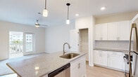 Located at 5214 Browning Ln in Leland, NC, this well-appointed one-bedroom, one-bathroom home offers a thoughtfully designed single-floor layout. The open-concept kitchen and living area serves as the heart of the home, featuring light hardwood-style flooring, a ceiling fan, and an abundance of natural light. The kitchen is equipped with crisp white shaker cabinetry, granite countertops, a subway tile backsplash, stainless steel appliances including a gas range, microwave, dishwasher, and refrigerator, and a central island with a undermount sink and pendant lighting. A dedicated pantry with wire shelving provides ample storage. The living area flows seamlessly from the kitchen, with plush carpeting and a sliding glass door that opens to a private balcony with outdoor views. The spacious bedroom features soft carpet, a ceiling fan, and a window offering natural light. A generously sized walk-in closet with wire shelving offers excellent storage capacity. The bathroom includes a full soaking tub and shower combination with white tile surround and built-in shelving. The overall ambiance is clean, bright, and modern, making this home a comfortable and functional living space.