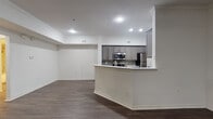 This single-story residence presents a well-organized layout with a clean, contemporary aesthetic. The open-concept living and dining area is finished with dark hardwood-style flooring and crown molding, contributing to a polished, cohesive look. Recessed lighting and a ceiling fan with a light fixture provide functional illumination throughout the main living space, which also benefits from a window allowing natural light to filter in.

The kitchen is designed for both utility and style, featuring gray cabinetry with a subway tile backsplash, light-colored countertops, and a full suite of stainless steel appliances including a refrigerator, range, and over-the-range microwave. A peninsula with a built-in sink and breakfast bar separates the kitchen from the living area, enhancing the open flow of the space.

The bedrooms are carpeted for comfort and include ceiling fans, generous windows with blinds, and access to closet space. One bedroom features a walk-in closet, while sliding glass doors in another provide outdoor access and additional natural light.

The bathroom is appointed with a soaking tub surrounded by tiled walls with decorative diamond accents, a granite-topped vanity, and hardwood-style flooring, rounding out a thoughtfully finished residence.
