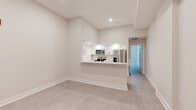 Located at 305 W Fourth St in downtown Winston-Salem, NC, this thoughtfully designed 2-bedroom, 1-bathroom unit offers a modern, move-in-ready layout with a clean, contemporary aesthetic throughout. The open-concept living and kitchen area centers around a sleek peninsula with white quartz countertops, white shaker cabinetry, subway tile backsplash, and a full suite of stainless steel appliances including a refrigerator, range, and built-in microwave. Tall ceilings amplify the sense of openness in the living area, which is finished with neutral-toned tile flooring that extends throughout the unit. A well-proportioned hallway connects the main living space to the bedrooms, bathroom, and closet. The primary bedroom is notably spacious and features large black-framed windows that flood the room with natural light and offer views of surrounding greenery. The second bedroom is a comfortable, well-lit space ideal for guests or a home office. The bathroom is finished with a glass-enclosed walk-in shower clad in classic white subway tile and brushed nickel fixtures. The overall palette of warm whites and soft neutrals gives the unit a bright, cohesive feel throughout.