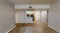 This single-floor unit offers a practical and well-organized layout designed for comfortable everyday living. The open-concept living area greets you upon entry, featuring wood-look plank flooring, neutral-toned walls, and a sliding glass door dressed with vertical blinds that allows natural light to filter in. A ceiling fan overhead provides additional comfort throughout the space.

The kitchen is positioned centrally and defined by a peninsula counter, offering a natural divide between the living and dining areas. It is equipped with warm-toned wood cabinetry, a gas range, over-the-range microwave, and a full-size refrigerator, all finished in black. Light-colored countertops complement the cabinetry and provide ample prep space.

The bedrooms continue the wood-look flooring theme and are finished with clean white walls, ceiling fans, and windows that bring in natural light. Each room offers a calm, functional environment suitable for a variety of uses.

Two bathrooms serve the unit — one featuring a soaking tub with tiled surround and a wood-cabinet vanity with a speckled countertop and large mirror, and a second with a combined tub and shower. Both bathrooms maintain a clean, neutral aesthetic consistent with the rest of the unit.
