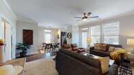 This thoughtfully designed single-floor residence offers a seamless open-concept layout connecting the living, dining, and kitchen areas. The living room is a welcoming focal point, anchored by a fireplace and outfitted with crown molding, a ceiling fan, and large windows that allow generous natural light to fill the space. A glass door provides direct access to a private balcony, offering outdoor views. The dining area accommodates a round table for four and features a door with transom window that also opens to the exterior, enhancing the flow of light throughout. The kitchen is equipped with dark espresso cabinetry, granite countertops, a subway tile backsplash, stainless steel appliances, and a window above the sink for additional natural light. The residence includes two well-sized bedrooms, each fitted with plush carpeting, large windows with outdoor views, and ceiling fans for comfort. The full bathroom features hardwood-style flooring, a dark vanity with granite countertops, and a full tub-shower combination. Throughout the home, hardwood-style flooring in the main living areas contrasts with soft carpet in the bedrooms, creating a warm and cohesive aesthetic.