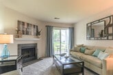 Located at 100 Runaway Bay Dr in Virginia Beach, Virginia, this single-floor residence offers a well-organized layout designed for comfortable everyday living. The living room serves as the heart of the home, centered around a tile-surround wood-burning fireplace with a white mantel. Soft carpeting, sliding glass doors, and views of the surrounding greenery create a warm, inviting atmosphere with ample natural light and direct access to a private patio. The galley-style kitchen is efficiently appointed with warm wood cabinetry, granite-style countertops, black appliances including a refrigerator and dishwasher, and tile flooring. A convenient laundry area is accessible directly from the kitchen. The residence includes multiple bedrooms, each featuring plush carpeting, large windows with outdoor views, and walk-in closets providing generous storage. Two bathrooms serve the home — a full bathroom with a tub/shower combination, granite-style vanity countertop, and tile flooring, and a second bathroom with a vanity and tile floor. Throughout, the neutral color palette and consistent finishes create a cohesive and functional living environment well-suited to the Virginia Beach lifestyle.