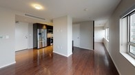This thoughtfully designed 2-bedroom, 2.5-bathroom residence offers a modern aesthetic throughout its single-floor layout. Rich hardwood flooring flows consistently through the open living area, connecting the living space to a well-appointed kitchen. The kitchen features dark espresso cabinetry, white quartz countertops, a subway tile backsplash, and a full suite of stainless steel appliances including a French door refrigerator, electric range, and built-in microwave. A large window in the living area admits generous natural light with views of the surrounding cityscape.

Both bedrooms are well-proportioned, each featuring tray ceilings with ceiling fans, hardwood floors, and walk-in closets. The primary bathroom is finished with dark wood vanity cabinetry, a white quartz countertop, a large illuminated mirror, and a glass-enclosed walk-in shower with mosaic tile flooring. The second full bathroom mirrors this refined style with a frameless glass shower, white subway tile surround, and a modern vanity. A separate powder room serves as the half bath, accented with large-format stone-look tile. The overall ambiance is clean, contemporary, and functional, making efficient use of every square foot.