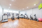 Located at 11 Margaret Ave in Kitchener, Ontario, this well-equipped fitness center offers a dedicated space for residents to maintain an active lifestyle. The room is finished with warm hardwood flooring that spans the entire area, complemented by clean white walls and recessed lighting that creates a bright, energizing atmosphere.

The cardio zone is well-stocked with multiple treadmills, elliptical trainers, and a recumbent bike, providing a variety of options for cardiovascular workouts. A row of horizontal windows along one wall allows natural light to filter into the space, enhancing the open feel of the room. Black-and-white fitness-themed artwork is displayed along the walls, adding a motivating visual element to the environment.

A dedicated strength training area features a multi-function cable machine and a weight bench, accompanied by a large wall-mounted mirror that allows users to monitor their form during exercise. A dumbbell rack provides additional free weight options.

Near the entrance, practical amenities include a water fountain, a wall-mounted television, and a dumbbell storage rack. The space is accessed through a secured door and is designed to serve as a convenient, fully functional fitness facility. The overall layout is thoughtfully organized to maximize usability while maintaining an uncluttered and motivating workout environment.