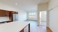This two-bedroom, one-bathroom residence in Sheboygan, Wisconsin offers a thoughtfully designed single-floor layout with a clean, modern aesthetic. The open-concept kitchen and living area serves as the heart of the home, featuring rich warm-toned cabinetry, a white subway tile backsplash, stainless steel appliances including a French door refrigerator and dishwasher, and a central island with a white countertop — ideal for both cooking and casual dining. Light wood-tone flooring runs throughout the main living areas, enhancing the bright, airy feel. The living room benefits from natural light through large windows overlooking an outdoor balcony railing, creating a welcoming and open atmosphere. Both bedrooms are comfortably sized, with the primary bedroom offering a generous footprint, plush carpeting, and a large window that fills the room with natural light. The second bedroom also features wood-style flooring and its own window with outdoor views. The bathroom is finished with light flooring, a soaking tub, and sleek matte black fixtures and hardware. A dedicated closet adds practical storage. Throughout the space, neutral wall tones and recessed lighting contribute to a clean, contemporary ambiance well-suited to modern living.