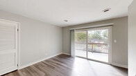 Located at 761-1A Adams Dr in Newport News, VA, this single-floor, 3-bedroom, 1-bathroom home offers a well-organized layout with a clean, modern aesthetic. The open-concept kitchen and dining area is outfitted with crisp white cabinetry, light wood-look vinyl flooring, stainless steel appliances including a refrigerator, range, microwave, and dishwasher, all set against neutral gray walls. The living room flows naturally from the main living area and features a sliding glass door that opens to an outdoor deck with views of surrounding greenery, filling the space with natural light. Each of the three bedrooms is finished with plush carpet, ceiling fans, and ample closet space — including the spacious primary bedroom, which features a double sliding-door closet. The bedrooms are painted in soft, neutral tones that contribute to a calm and comfortable atmosphere. The bathroom includes a full tub and shower surround in clean white. Additional functional spaces include a pantry, utility room, laundry area, and multiple closets throughout, providing generous storage. Two hallways connect the rooms efficiently, making the layout practical and easy to navigate. The overall design emphasizes low-maintenance, move-in-ready living.