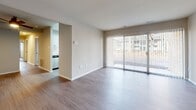 Located at 7000 Coachman Lane in Henrico, Virginia, this single-floor unit offers a clean, updated interior with a cohesive neutral color palette throughout. The living area is an open, airy space finished with wood-style laminate flooring and anchored by a large sliding glass door that allows abundant natural light and provides views of the surrounding exterior. The layout connects seamlessly to the kitchen, which features white shaker-style cabinetry with matte black hardware, bright white quartz countertops, a classic subway tile backsplash, a stainless steel undermount sink with a black pull-down faucet, and a stainless steel dishwasher. The bedrooms are carpeted and well-proportioned, each offering neutral walls and natural light from windows. Storage is well-considered, with closets — including a walk-in — present in the bedroom areas. The bathrooms are finished with white vanities topped with light stone-style counters, undermount sinks, matte black fixtures, and large mirrors. Wood-look flooring in the bathrooms complements the overall design. The unit presents a consistent, modern aesthetic throughout.