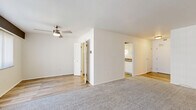 Located at 12540 Edgewater Drive in Lakewood, Ohio, this one-bedroom, two-bathroom residence offers a clean and functional layout across a single floor. The living room is a generously sized, carpet-floored space featuring a ceiling fan, a wide bank of vertical-blind-covered windows that invite natural light, and a baseboard heating unit beneath the sill. The room's open feel connects seamlessly to the rest of the home. The kitchen is outfitted with white cabinetry, laminate wood-style flooring, ample counter space, and white appliances including an electric range and a full-size refrigerator. The spacious primary bedroom features soft carpet, a ceiling fan, a louvered closet, and a connection to a walk-in closet with built-in shelving and hanging rods for generous storage. Two bathrooms serve the residence: one includes a full tub-shower combination with a stylish gray vanity and mirrored medicine cabinet, while the second offers a refined gray vanity with a white countertop, bright vanity lighting, and wood-style flooring. The overall aesthetic throughout is light and neutral, with white walls and a clean, move-in-ready presentation.