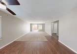 Located at 7611 Lighthouse Dr in Stockton, California, this single-story, three-bedroom, two-bathroom home offers a practical and comfortable layout across a well-utilized floor plan. The open-concept living and dining area is a central highlight, featuring rich hardwood-style flooring that transitions seamlessly into plush carpeting, a ceiling fan, and sliding glass doors flanked by a window that invite natural light and provide direct access to the fenced backyard. The kitchen is designed for functionality, showcasing white cabinetry, white appliances including a refrigerator, range, and microwave, and a peninsula with an overhang that serves as a breakfast bar. A dedicated window brightens the kitchen and adjacent dining area. The three bedrooms are carpeted and finished in neutral tones, offering a calm atmosphere. The spacious primary bedroom features sliding glass doors leading to the backyard and an additional window for natural light. The secondary bedrooms include closets and windows with blinds. The two bathrooms feature hardwood-style flooring, with one including a shower-tub combination with sliding glass doors. Hallways connect the bedrooms and bathrooms efficiently, completing this well-organized single-level home.