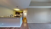 Located on E New York Street in Aurora, Illinois, this two-story residence offers a well-organized layout across two distinct levels. The main level opens into a combined living and kitchen area distinguished by wood-style hard flooring that contrasts with plush carpeting in the living zone. The kitchen is equipped with dark cabinetry, stone-look countertops, a peninsula with a built-in sink featuring a matte black faucet, and a full suite of stainless steel appliances including a range, microwave, and refrigerator. A dedicated laundry area is conveniently tucked along the hallway on this level. A white-railed staircase with carpeted treads connects the main level to the upper floor. The upper level features wall-to-wall carpeting, neutral-toned walls, and a ceiling fan, contributing to a comfortable atmosphere. A full bathroom on this floor includes a tub-shower combination with sliding glass doors, stone-tile flooring, a vanity with stone-look countertops, and dark cabinetry. A bedroom on this level includes a sliding glass door and a built-in niche detail, adding architectural character. The overall ambiance is clean, functional, and move-in ready.