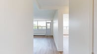 Located on the fourth floor at 3390 Keele Street in Toronto's north end, this one-bedroom, one-bathroom unit offers a well-organized layout with a clean, modern aesthetic throughout. Light wood laminate flooring runs continuously through the living spaces, complementing the crisp white walls and creating a bright, airy atmosphere.

The living room is a generous open area anchored by a wide bank of floor-to-ceiling windows that flood the space with natural light and frame open outdoor views of the surrounding neighbourhood. A balcony door provides access to the exterior, extending the sense of openness.

The galley-style kitchen is efficiently designed with white cabinetry, a subway tile backsplash, stainless steel appliances including a refrigerator, electric range, built-in microwave, and dishwasher, along with recessed lighting overhead.

The bedroom is a comfortable, well-proportioned room featuring large windows that continue the natural light theme found throughout the unit. A built-in closet provides ample storage, and the neutral palette keeps the room feeling calm and versatile.

The bathroom is finished with full white subway tile surrounding a soaker tub and shower combination, paired with clean white fixtures for a polished, uniform look. The overall unit presents a move-in ready, refreshed interior ideal for comfortable urban living.