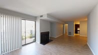 Located in the Saddlebrook neighborhood of Lexington, Kentucky, this single-floor residence offers a thoughtfully arranged layout visible across its interconnected living spaces. The main living area makes a strong impression with light hardwood-style flooring, neutral gray walls, and a classic fireplace with a dark surround serving as a natural focal point. A large sliding glass door floods the space with natural light and provides direct access to an outdoor patio area, where greenery is visible beyond. Vertical blinds frame the door, offering adjustable privacy and light control.

The open layout connects seamlessly to additional living or dining space, maintaining the same clean hardwood flooring and a simple, modern aesthetic throughout. The kitchen is well-appointed, featuring dark espresso cabinetry that contrasts sharply with light speckled countertops, a stainless steel double-basin sink, a stainless dishwasher, and a black electric range. Ample upper and lower cabinet storage provides functional utility.

The bedroom is generously proportioned, finished with plush carpet and a sliding glass door with vertical blinds that introduce additional natural light. The bathroom presents a straightforward, clean design with a vanity featuring dark cabinetry, a wide mirror with built-in shelving, and a separate toilet compartment. Throughout the space, the consistent neutral color palette and practical finishes create a cohesive, move-in-ready environment.