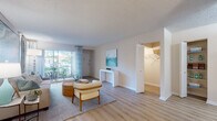 Located at 4200 Community Dr in West Palm Beach, Florida, this single-floor residence offers a well-designed layout with a cohesive coastal aesthetic throughout. Light wood-style flooring flows seamlessly across the main living areas, complementing the neutral color palette and textured ceilings found throughout the space.

The living room serves as the central gathering area, featuring a large sliding glass door that fills the room with natural light and provides a view of the outdoor surroundings. A separate seating area connects to a dedicated dining space and a functional kitchen equipped with rich cherry wood cabinetry, granite-style countertops, and black appliances including a refrigerator and electric range.

The bedroom is a comfortable retreat with soft carpeting, ample wall space, and access to a generously sized walk-in closet fitted with built-in shelving and hanging rods. The bathroom features tile-surround tub and shower combination, a wood-toned vanity with stone countertop, and light wood flooring.

Throughout the residence, the design maintains a light, airy atmosphere reminiscent of coastal Florida living, with consistent finishes and a practical, open flow between rooms that makes the space feel welcoming and functional.