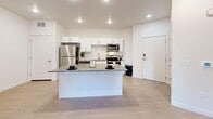 Located at 1776 W 4100 S in West Valley City, Utah, this well-designed one-bedroom, one-bathroom unit offers a clean, modern aesthetic with thoughtful use of space throughout. The open-concept kitchen and living area serves as the heart of the home, featuring light wood-look flooring, recessed lighting, and a central kitchen island with a gray countertop that doubles as a breakfast bar. The kitchen is equipped with stainless steel appliances, crisp white cabinetry, and a subway tile backsplash, delivering both style and functionality. French doors in the living area open directly to a private, fenced patio — an ideal outdoor retreat with a concrete floor and wood-panel privacy fencing. The bedroom is carpeted for comfort, includes a ceiling fan, a window with blinds for natural light, and connects to a spacious walk-in closet with built-in shelving and hanging rods. A second closet provides additional storage. The full bathroom features a white vanity with a gray countertop, a large mirror, and a tub-shower combination with clean white tile surround. A dedicated laundry area rounds out the unit's practical amenities. The overall aesthetic is bright, neutral, and move-in ready.