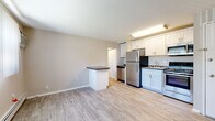 Located at 615 Main St in Amherst, Massachusetts, this single-floor unit offers a clean, functional layout designed for comfortable everyday living. The open-concept kitchen and living area serves as the heart of the space, featuring light gray wood-look flooring that runs throughout. The kitchen is equipped with stainless steel appliances, including a full-size refrigerator, electric range, built-in microwave, and dishwasher. White shaker-style cabinetry with dark countertops provides ample storage and prep space, while a peninsula with a dark countertop top creates a natural division between the kitchen and living area. The living area is bright, aided by a window with vertical blinds and a wall-mounted air conditioning unit, ensuring year-round comfort alongside the baseboard heating system. A hallway leads to the private bedroom, which features soft wall-to-wall carpeting, two windows allowing for natural light, and baseboard heating. The bathroom includes a full shower-tub combo with clean white surround, brushed nickel fixtures, and wood-look flooring. A closet is accessible from the hallway, adding practical storage to this thoughtfully designed unit.