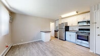 Located at 615 Main St in Amherst, Massachusetts, this single-floor unit offers a clean, functional layout designed for comfortable everyday living. The open-concept kitchen and living area serves as the heart of the space, featuring light gray wood-look flooring that runs throughout. The kitchen is equipped with stainless steel appliances, including a full-size refrigerator, electric range, built-in microwave, and dishwasher. White shaker-style cabinetry with dark countertops provides ample storage and prep space, while a peninsula with a dark countertop top creates a natural division between the kitchen and living area. The living area is bright, aided by a window with vertical blinds and a wall-mounted air conditioning unit, ensuring year-round comfort alongside the baseboard heating system. A hallway leads to the private bedroom, which features soft wall-to-wall carpeting, two windows allowing for natural light, and baseboard heating. The bathroom includes a full shower-tub combo with clean white surround, brushed nickel fixtures, and wood-look flooring. A closet is accessible from the hallway, adding practical storage to this thoughtfully designed unit.