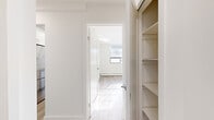 This thoughtfully designed single-floor residence offers three bedrooms, two bathrooms, a kitchen, and dedicated hallway and closet spaces within a compact yet functional layout. Throughout the home, light wood laminate flooring and crisp white walls create a clean, contemporary aesthetic that maximizes the sense of openness.

The galley-style kitchen is a standout feature, finished with white shaker cabinetry, stone-look countertops, a subway tile backsplash, recessed lighting, and a full suite of stainless steel appliances including a refrigerator, stove, microwave, and dishwasher.

The spacious primary bedroom receives generous natural light through large grid-paned windows and is complemented by a mirrored sliding-door closet, adding both storage and depth to the room. The additional bedrooms share the same light-filled, minimalist character with natural light streaming in through well-positioned windows and baseboard heating along the perimeter walls.

Both bathrooms are finished with clean, modern fixtures. One features a soaking tub with classic white subway tile surround and chrome hardware, while the other includes a stone-composite vanity countertop with an undermount sink and large mirror.

Connecting the rooms, the hallways provide efficient circulation, with a built-in shelving unit offering additional storage. The overall ambiance is bright, fresh, and move-in ready.