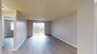 Located at 14095 SW Walker Rd in Beaverton, Oregon, this single-floor unit offers a practical and well-appointed layout designed for comfortable everyday living. Throughout the space, wood-style plank flooring provides a clean, cohesive look, complemented by neutral-toned walls and textured ceilings.

The living area is a standout feature, offering generous open floor space and a large sliding glass door fitted with vertical blinds that floods the room with natural light and provides direct access to an outdoor patio or balcony. A wall-mounted thermostat and light switch panel are conveniently positioned near the entry.

Adjacent to the living space, the galley-style kitchen is efficiently laid out with white cabinetry above and below the counters, a stainless sink, and includes a full-size refrigerator and range. A doorway at the end of the kitchen leads to additional storage or utility space.

The bedroom is a well-proportioned, quiet room featuring the same wood-style flooring, a textured ceiling, and a window that allows in natural light. The full bathroom is clean and functional, equipped with a soaking tub and shower combination, a vanity with storage, and wood-style flooring. A ceiling fan in the secondary area adds to the overall comfort of the unit.
