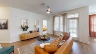 This single-floor residence at 2571 Seminole Trail in Charlottesville, Virginia, presents a well-designed open-concept layout that connects the living, dining, and kitchen areas into a cohesive and functional space. Warm hardwood-style flooring runs throughout the main living areas, complemented by crisp white walls that enhance the sense of brightness and airiness.

The living room features a ceiling fan, large windows, and a glass door leading to an outdoor balcony, allowing generous natural light and outdoor views. An adjacent dining nook benefits from multiple windows dressed with elegant drapes, creating a welcoming atmosphere for meals.

The kitchen is a standout feature, outfitted with white shaker cabinetry, granite countertops, a central island with bar seating, stainless steel appliances, a tile backsplash, and pendant lighting. Ample counter and storage space make it highly functional.

The bedrooms offer plush carpeting, ceiling fans, and well-sized windows. The bathroom includes granite-topped white vanity cabinetry, a large mirror, and wood-style flooring. Additional highlights include a walk-in closet and a clean, neutral palette throughout, lending the space a modern yet inviting character.