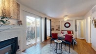 This thoughtfully designed single-floor studio maximizes its compact footprint through an efficient, open layout. The main living area serves as the central hub of the space, featuring warm wood-look flooring, a textured ceiling, and a ceiling fan fixture. A large sliding glass door dominates one wall, flooding the interior with natural light and providing direct access to a private outdoor patio area, offering a seamless indoor-outdoor connection.

Built-in white cabinetry lines the wall adjacent to the sleeping area, providing organized storage while maintaining a clean, cohesive aesthetic. A decorative circular mirror adds a visual accent to the white walls.

The galley-style kitchen is separately defined and efficiently arranged, featuring white cabinetry on both sides, light speckled countertops, a stainless steel sink, a full-size refrigerator, and a dishwasher. Stone tile flooring distinguishes this space from the rest of the unit.

The walk-in closet offers dedicated storage with built-in shelving, a hanging rod, and matching wood-look flooring. The bathroom includes a shower-tub combination, a vanity with speckled countertop, and overhead cabinetry, completing this well-organized, compact living space.