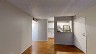 This single-floor residence offers a cohesive and functional layout highlighted by warm wood-look flooring that runs throughout the living areas, bedrooms, and kitchen. The open living area connects seamlessly to the kitchen via a pass-through window framed by a contrasting gray accent wall, creating a sense of openness and visual interest. The kitchen is designed for practicality, featuring white shaker cabinetry, subway tile backsplash, light-toned countertops, stainless steel appliances including a refrigerator and range, and a double-basin sink. A dedicated laundry area is accessible directly from the kitchen. The bedrooms are bright and airy, benefiting from multiple windows dressed with horizontal blinds that allow natural light to filter in. One bedroom features sliding glass door access, adding versatility to the space. The bathroom is finished with a modern vessel sink, a large wall mirror with overhead lighting, and light-toned tile flooring. Textured ceilings are present throughout the unit, and neutral gray walls provide a clean, move-in-ready backdrop across all rooms. The overall layout is efficient and well-connected, making this a practical and comfortable living space.