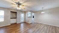 This single-floor space offers a well-organized layout with a cohesive neutral color palette and warm wood-look flooring that runs consistently throughout the unit. The open living and dining area serves as the heart of the space, featuring a ceiling fan with integrated lighting, a textured popcorn ceiling, and a glazed rear door that introduces natural light. A pendant light fixture marks the dining zone, while a chair rail detail along the wall adds a subtle architectural accent.

A pass-through opening with a granite-style countertop ledge connects the living area to the kitchen, enhancing the sense of openness between the two spaces. The kitchen is well-appointed with white shaker-style cabinetry, dark laminate countertops, a double basin sink beneath a window, and black appliances including a dishwasher and range. A built-in nook near the living area provides additional cabinetry with dark countertop accents.

The bedrooms are comfortably sized, each with wood-look flooring, neutral walls, and windows that draw in natural light. The bathroom features white shaker vanity cabinetry topped with dark laminate counters, a white undermount sink, and a tub-shower combination with tiled surround, all finished with wood-look flooring for a consistent aesthetic throughout.