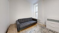 Located at 1245 Rue Saint-Marc in Montréal, this single-floor unit offers three bedrooms, one bathroom, a living room, and a kitchen, all presented in a clean, bright, all-white palette throughout.

The kitchen is efficiently designed with white cabinetry extending to the ceiling, a stainless steel refrigerator, and a stainless steel electric range positioned beneath a window that draws in natural light. Light hardwood flooring runs throughout the unit, contributing to the overall sense of brightness and continuity.

The living room is a compact yet functional space featuring a window with a radiator beneath it, crown moulding, and light hardwood floors. The primary bedroom is a notable highlight, featuring a decorative white fireplace mantel and a large window, adding architectural character. A second bedroom also benefits from a window, while the third bedroom is a more compact room suited for a single bed and desk setup.

The bathroom is finished with large-format grey tiles in the walk-in shower, complemented by clean white walls and tile flooring, creating a modern, minimal aesthetic. A welcoming hallway connects all rooms, and panel-style interior doors maintain a cohesive, contemporary look throughout.